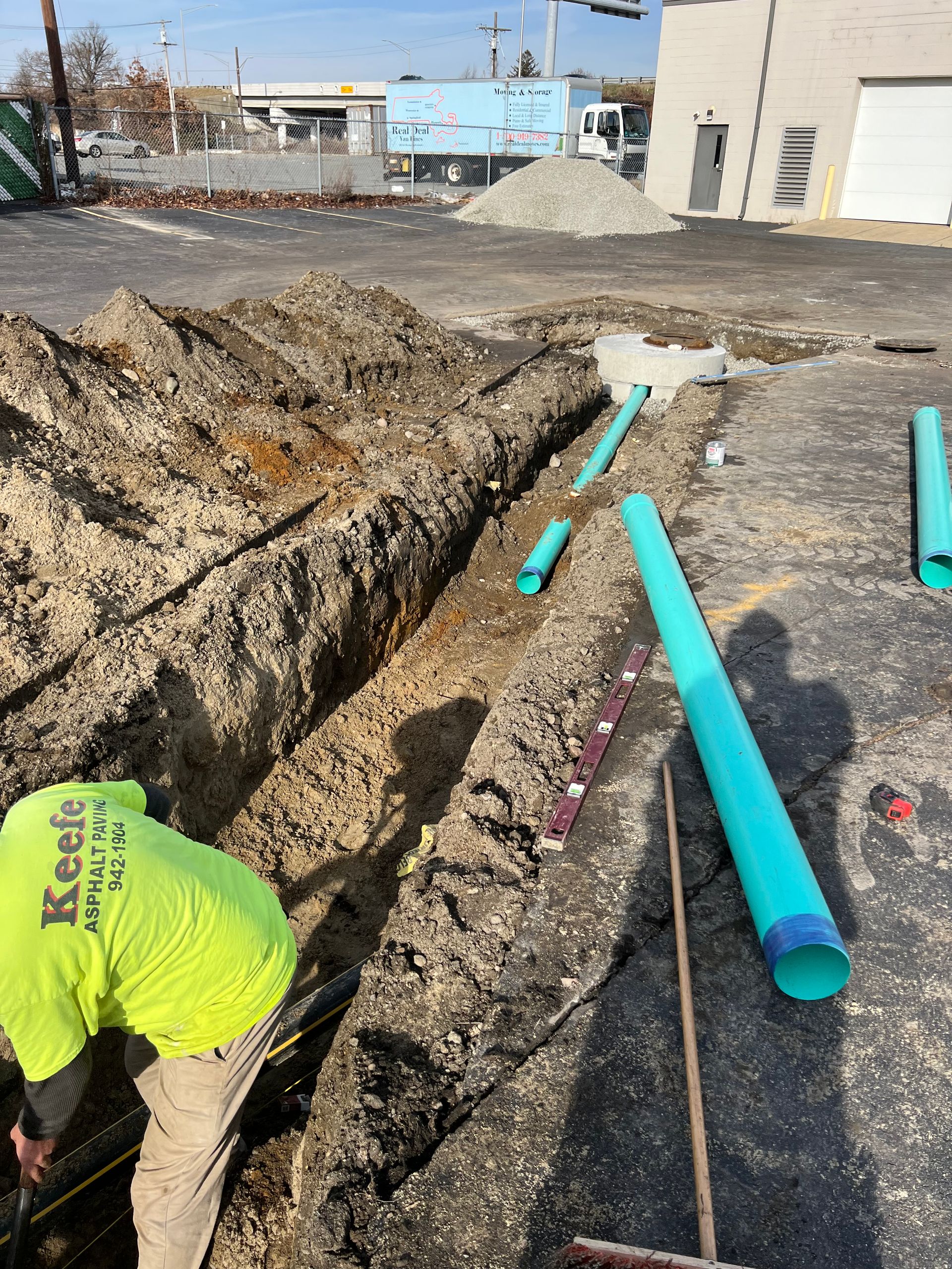 A man is digging a hole in the ground with green pipes.