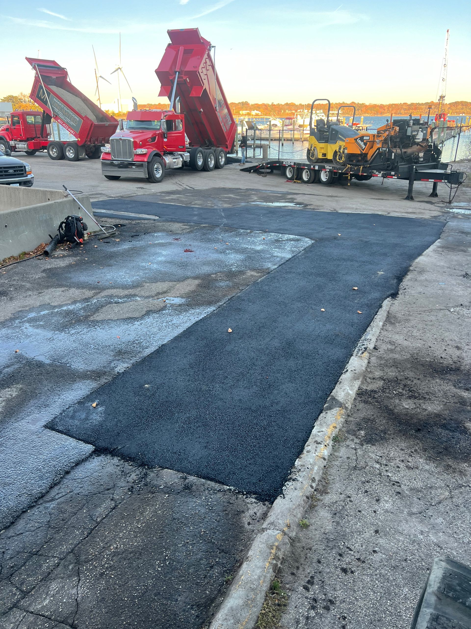A row of dump trucks are parked in a parking lot.