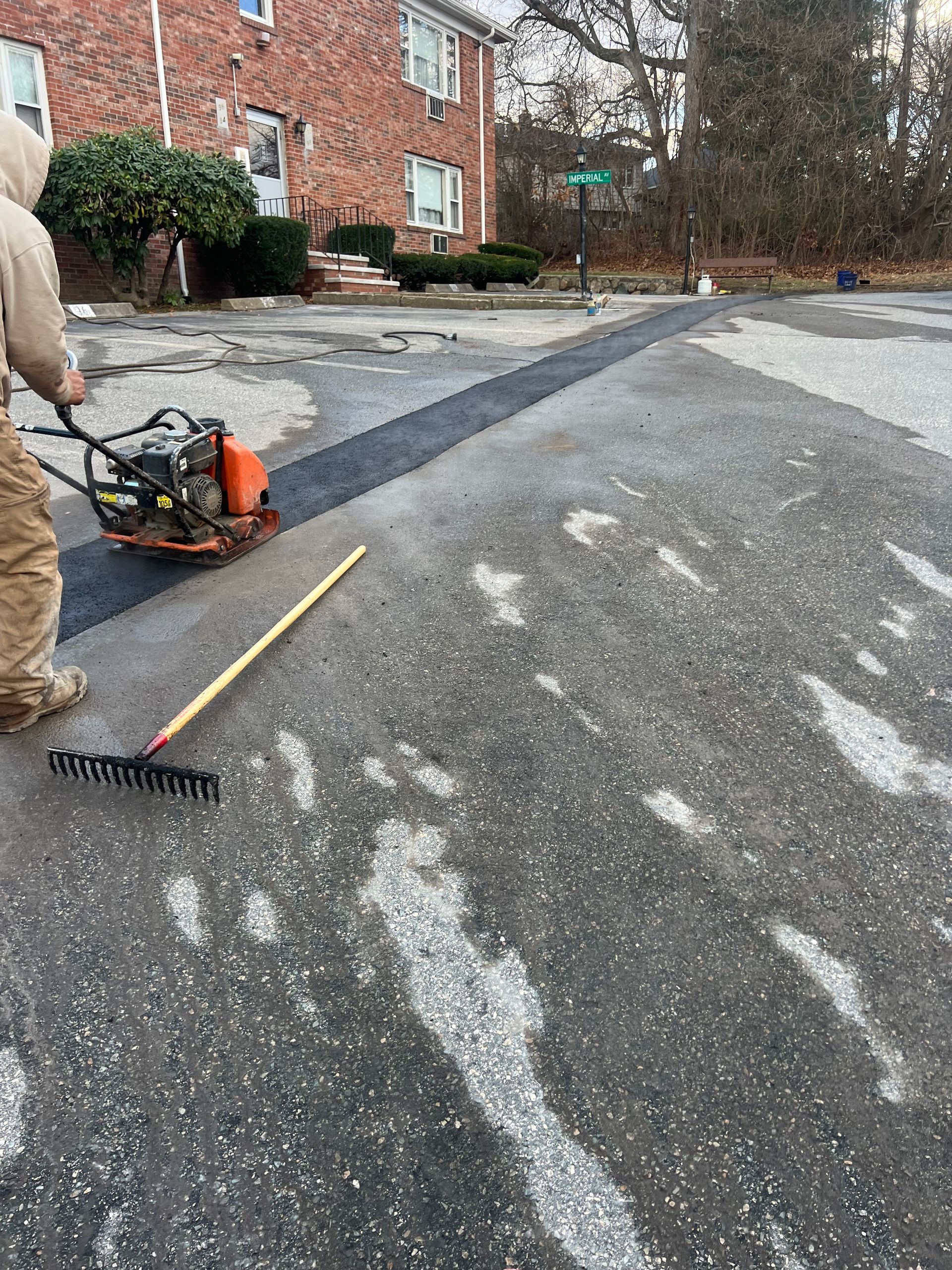 A man is raking the asphalt in a parking lot.