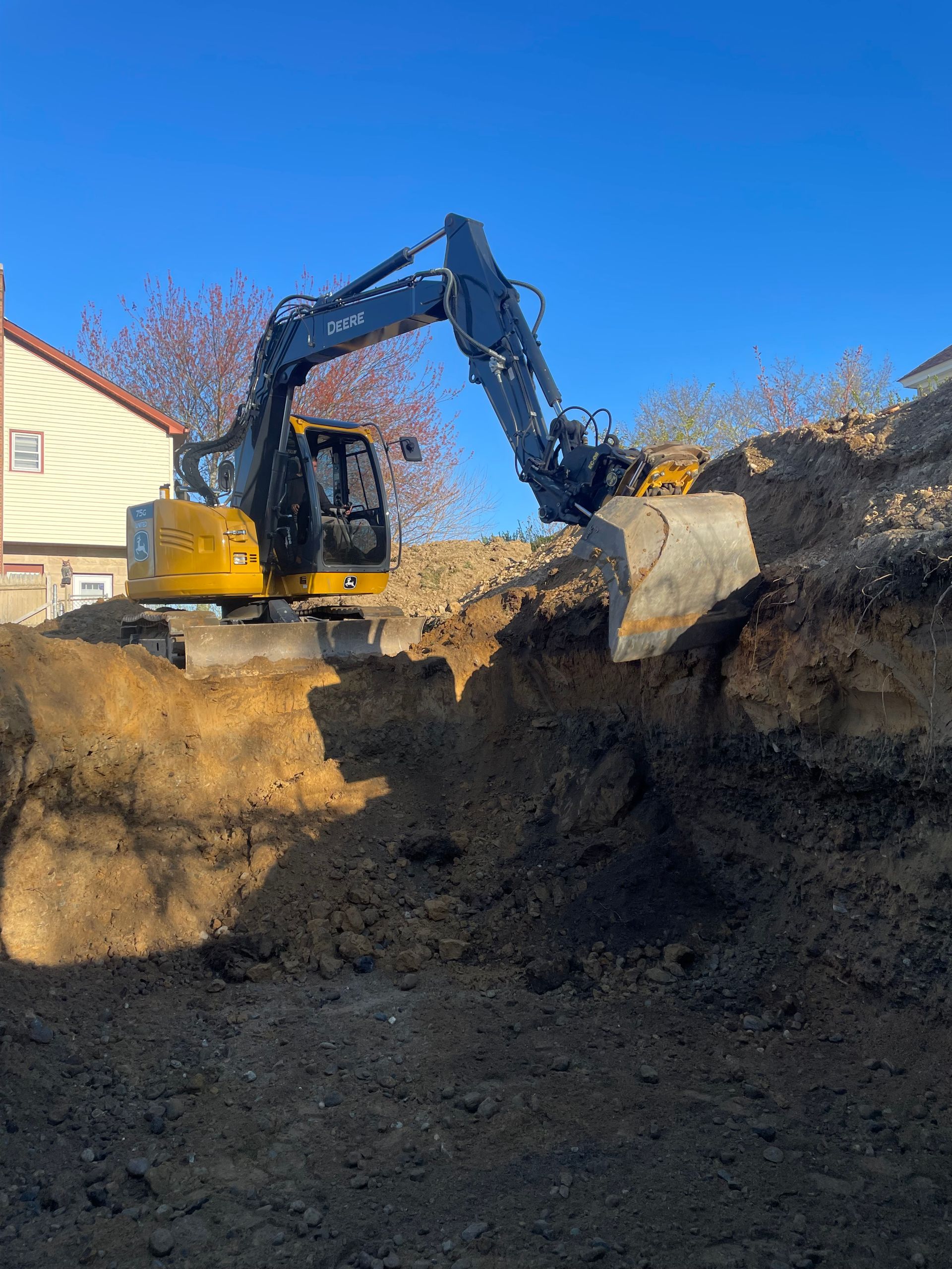 A yellow excavator is digging a hole in the ground.