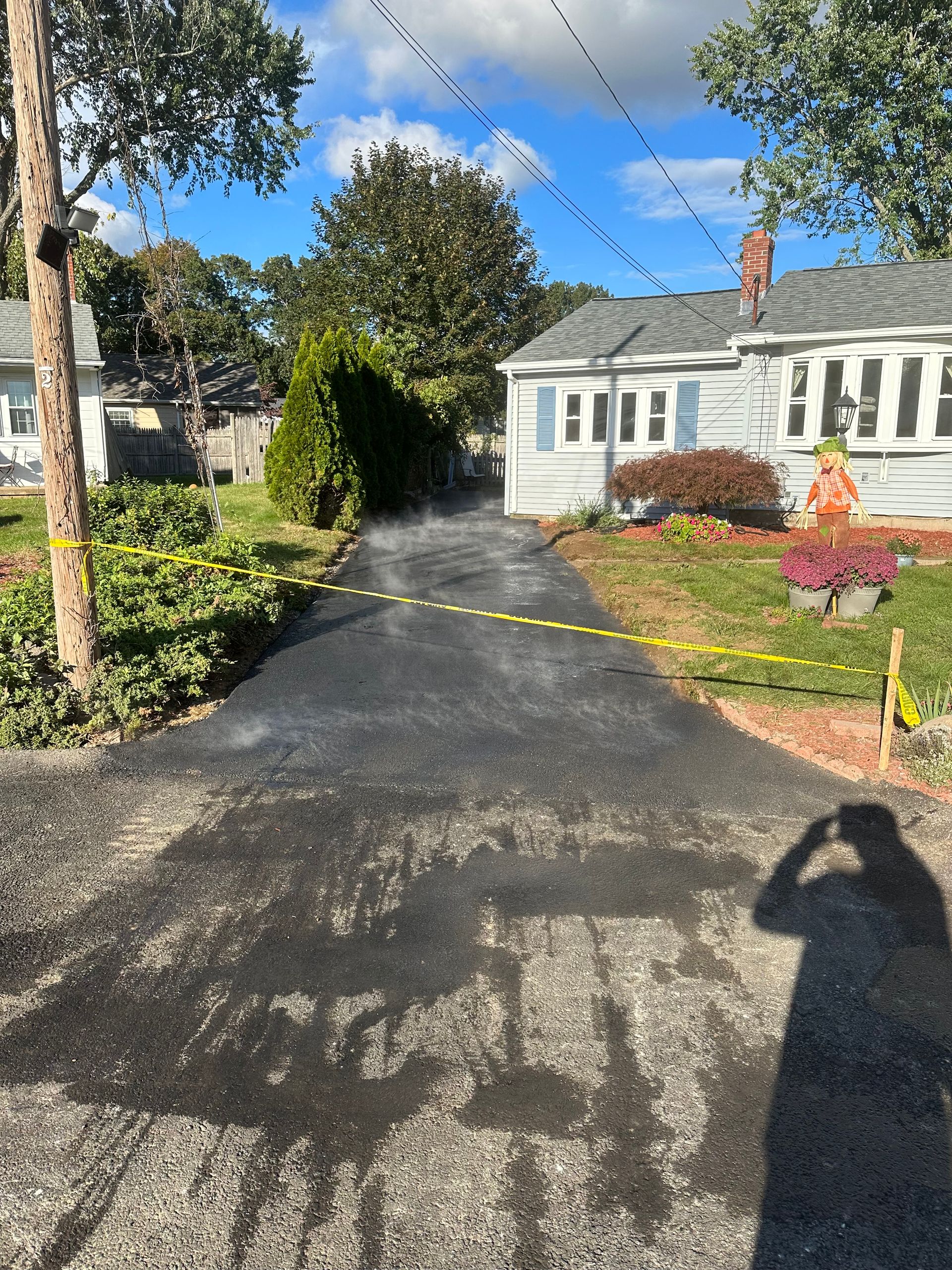 A person is taking a picture of a driveway in front of a house.