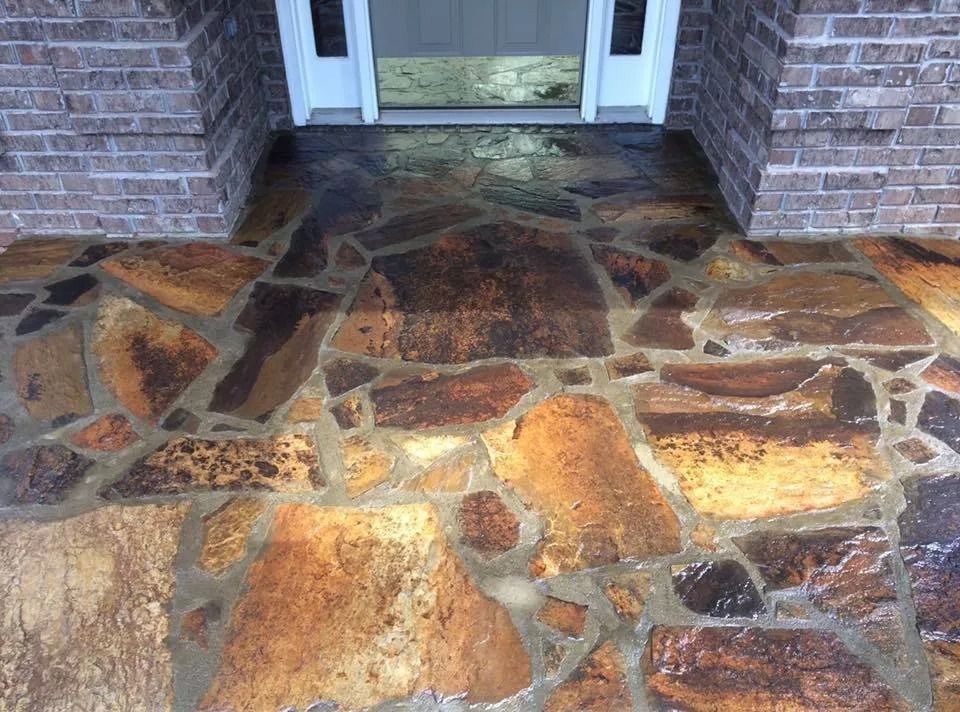 Flagstone porch walkway with varied brown, tan, and dark grey natural stones leading to a front entryway.