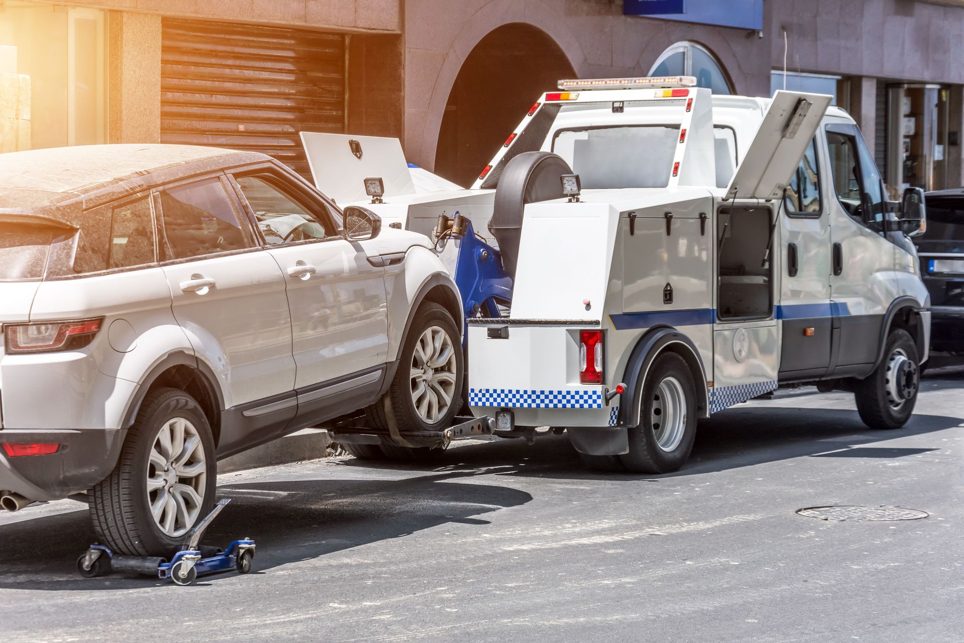 Tow truck towing a white SUV on a city street.