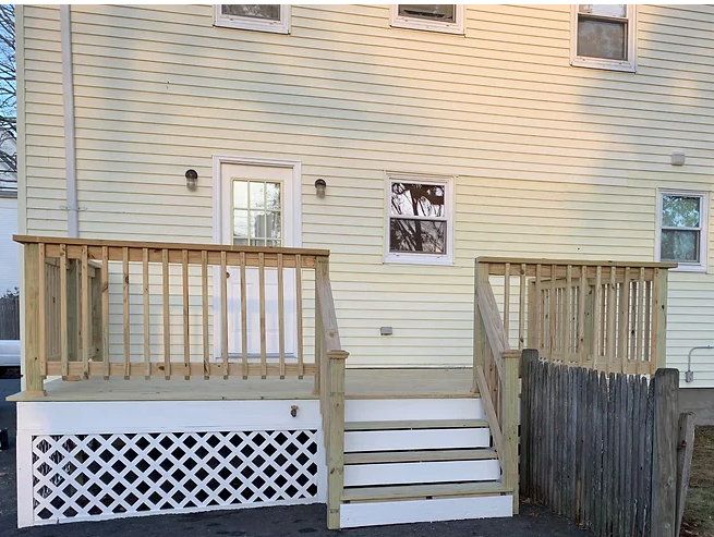 The back of a house with a wooden deck and stairs