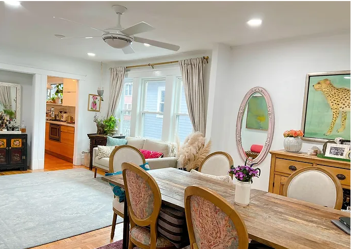 A living room with a dining table and chairs and a ceiling fan.