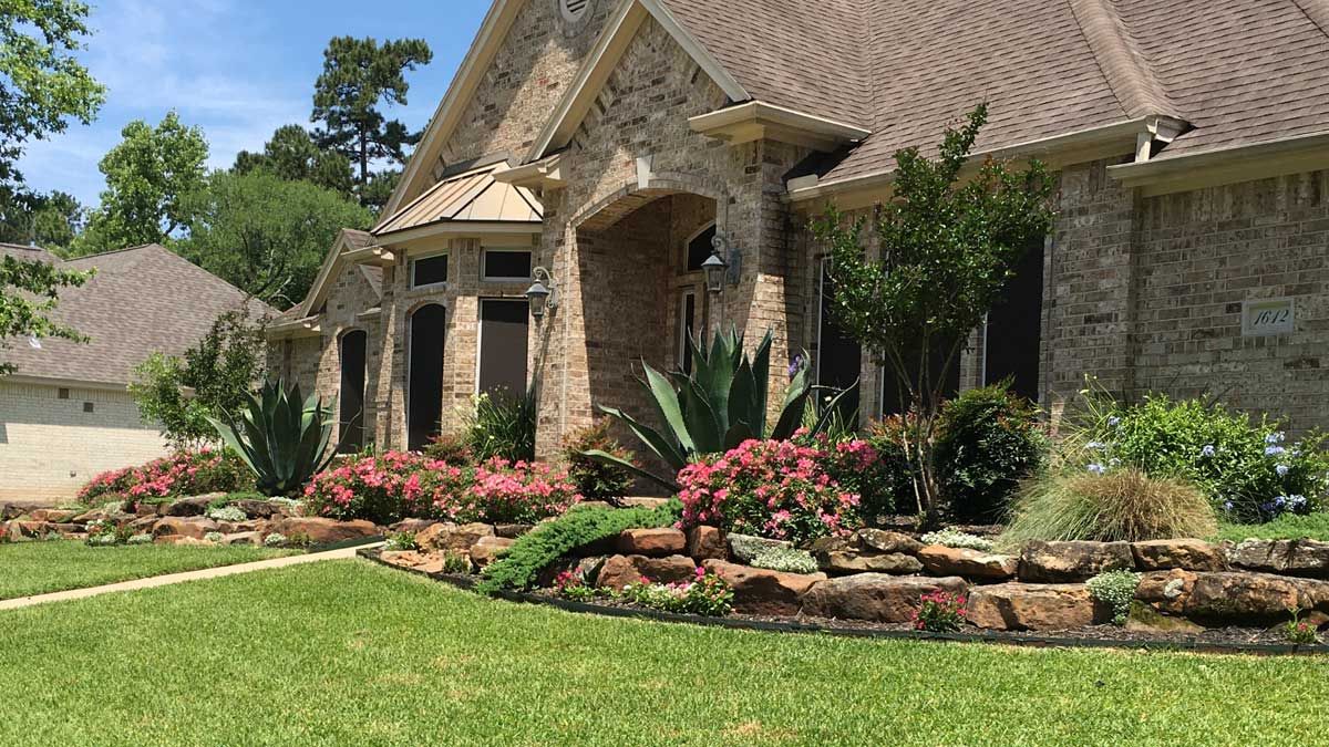 Stone house with landscaped front yard; red flowers and succulents line a stone border.