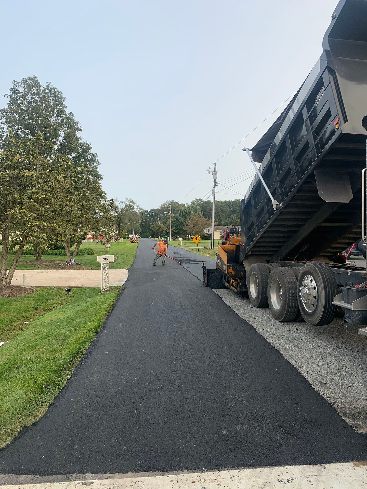 A dump truck is sitting on the side of a road.