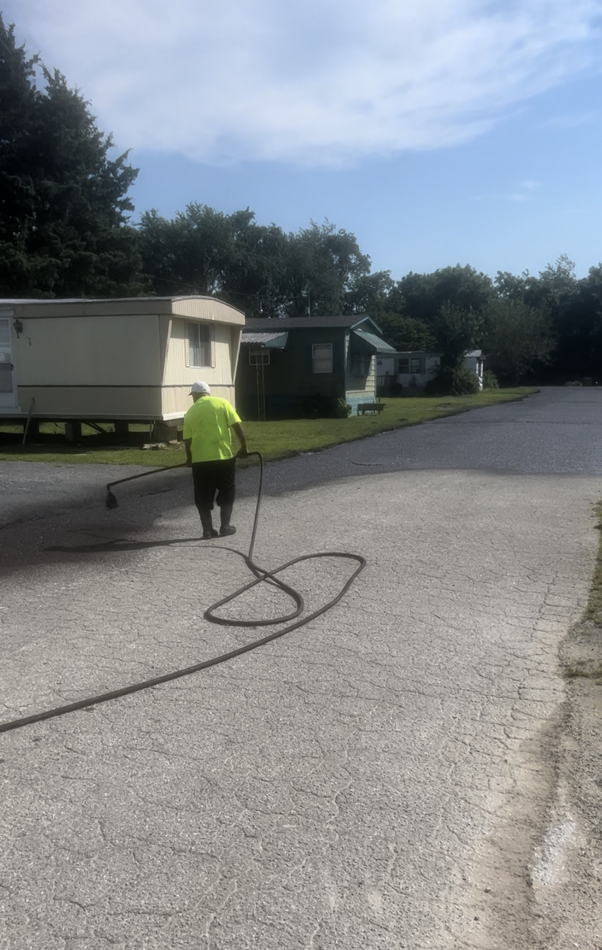 A man is walking down a road with a hose.