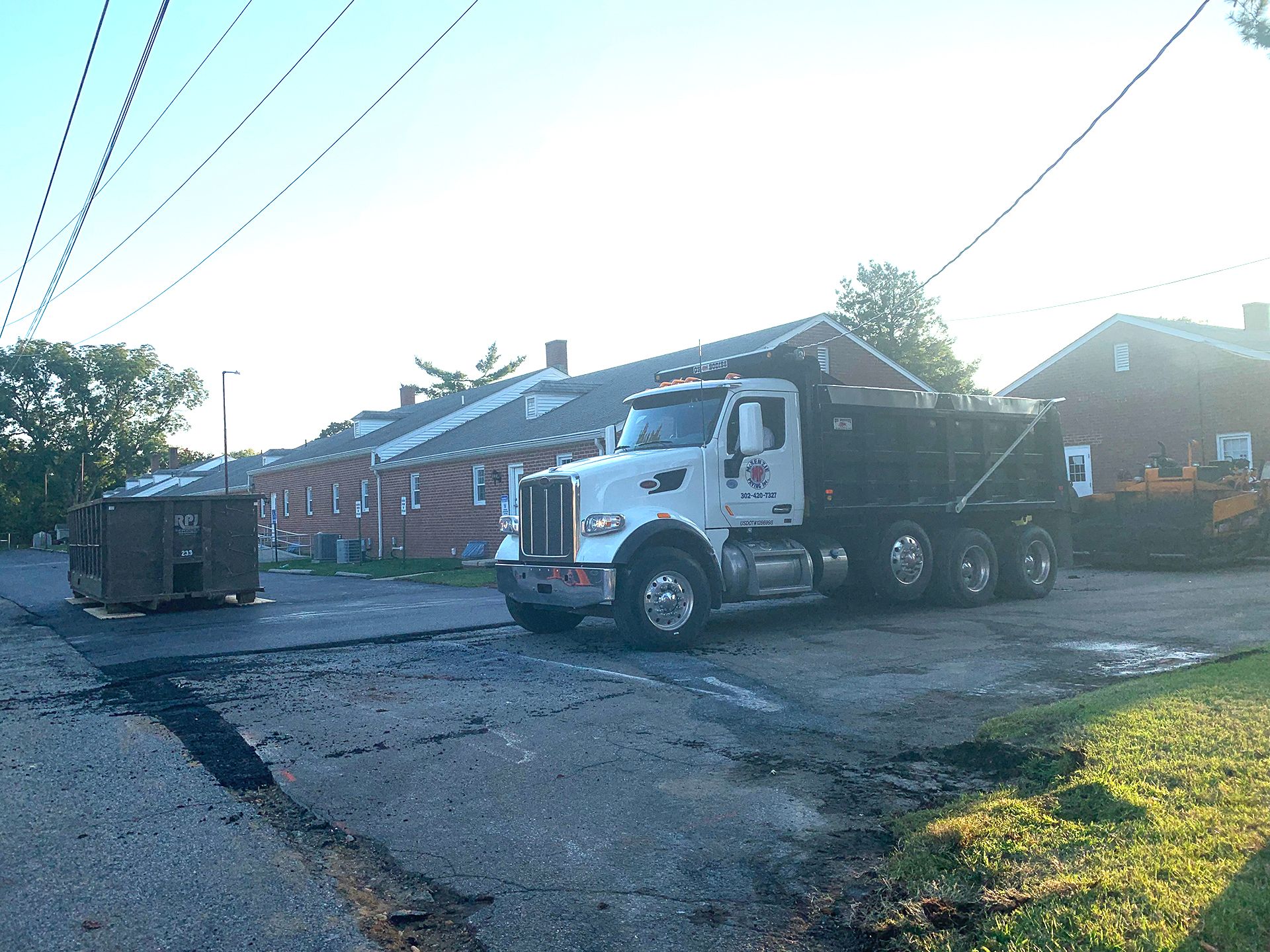 A dump truck is parked on the side of the road in front of a building.