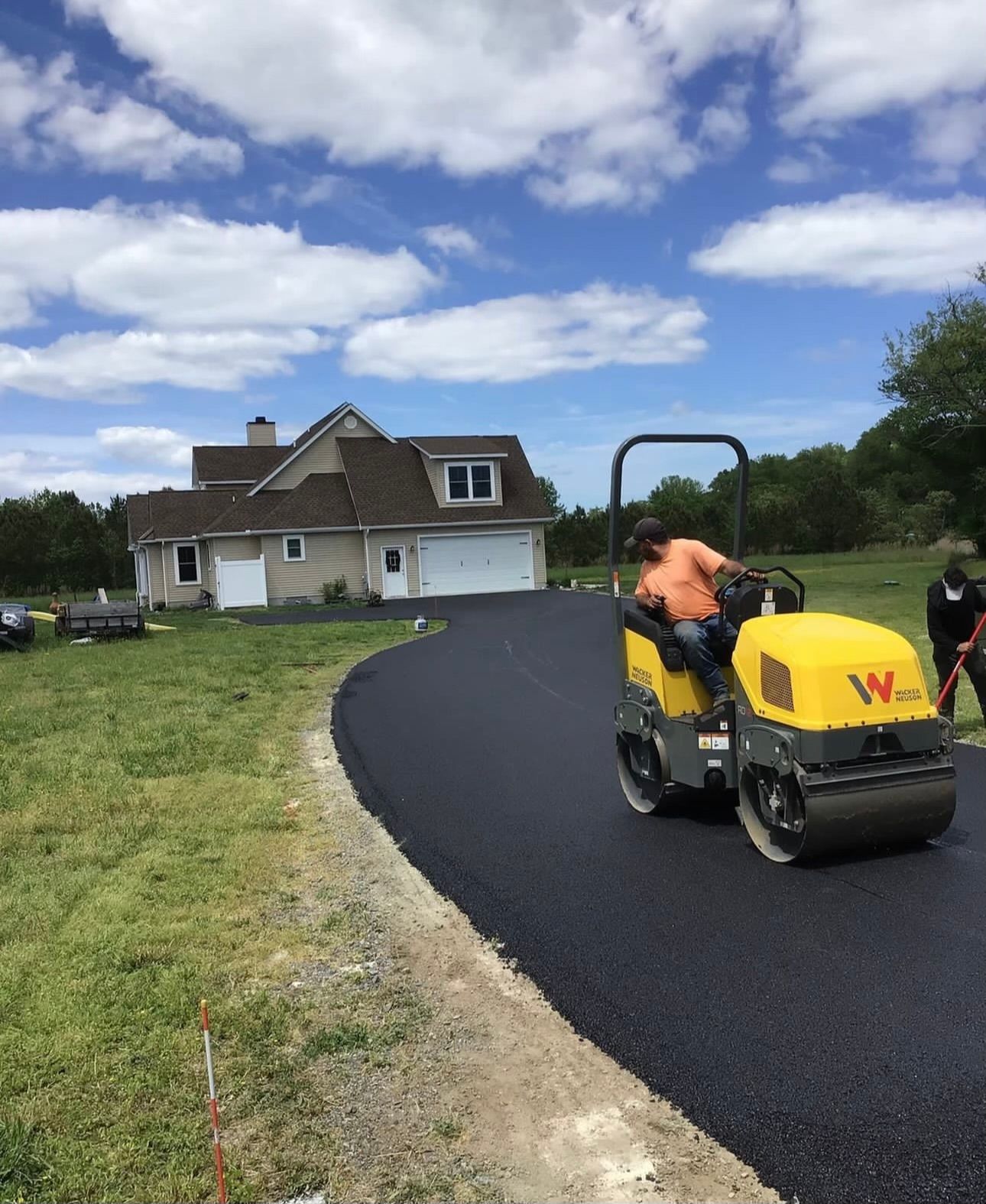 A man is riding a yellow roller on a road in front of a house.
