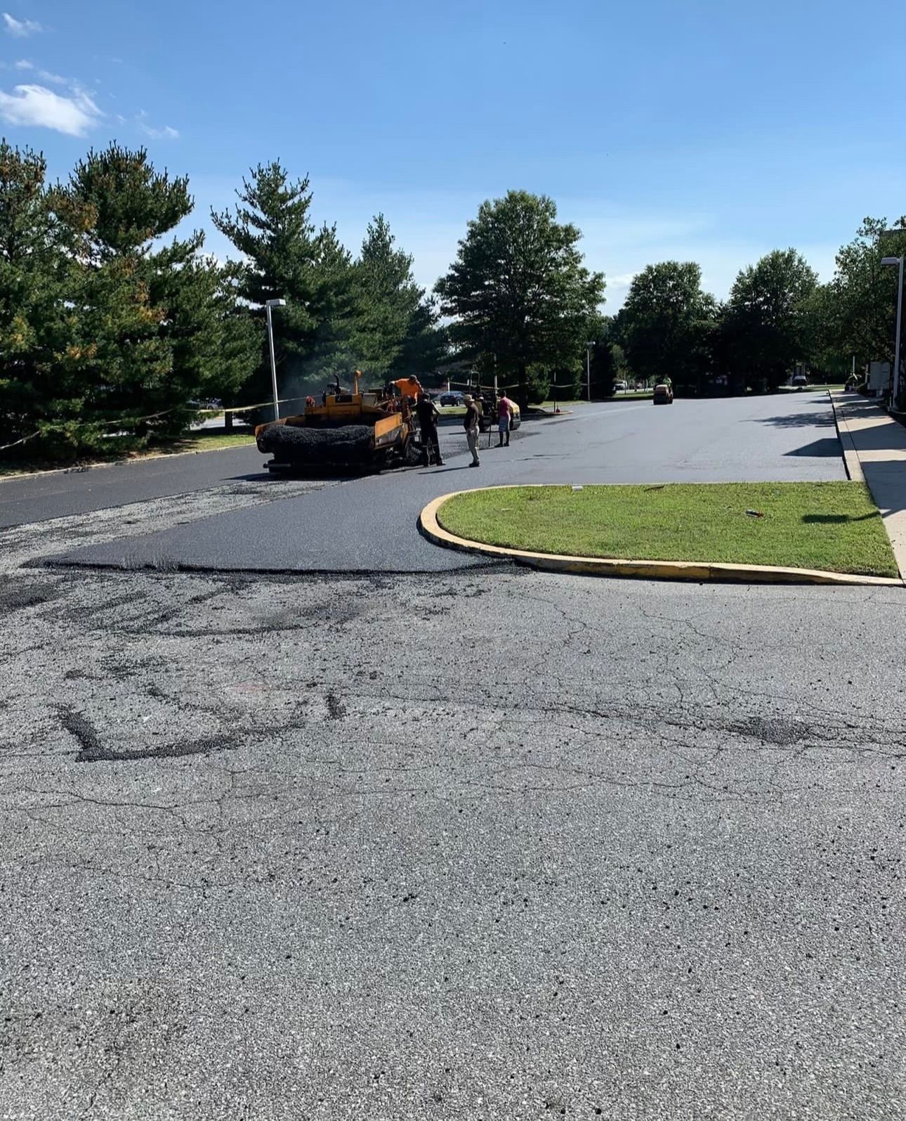 A parking lot is being paved on a sunny day.