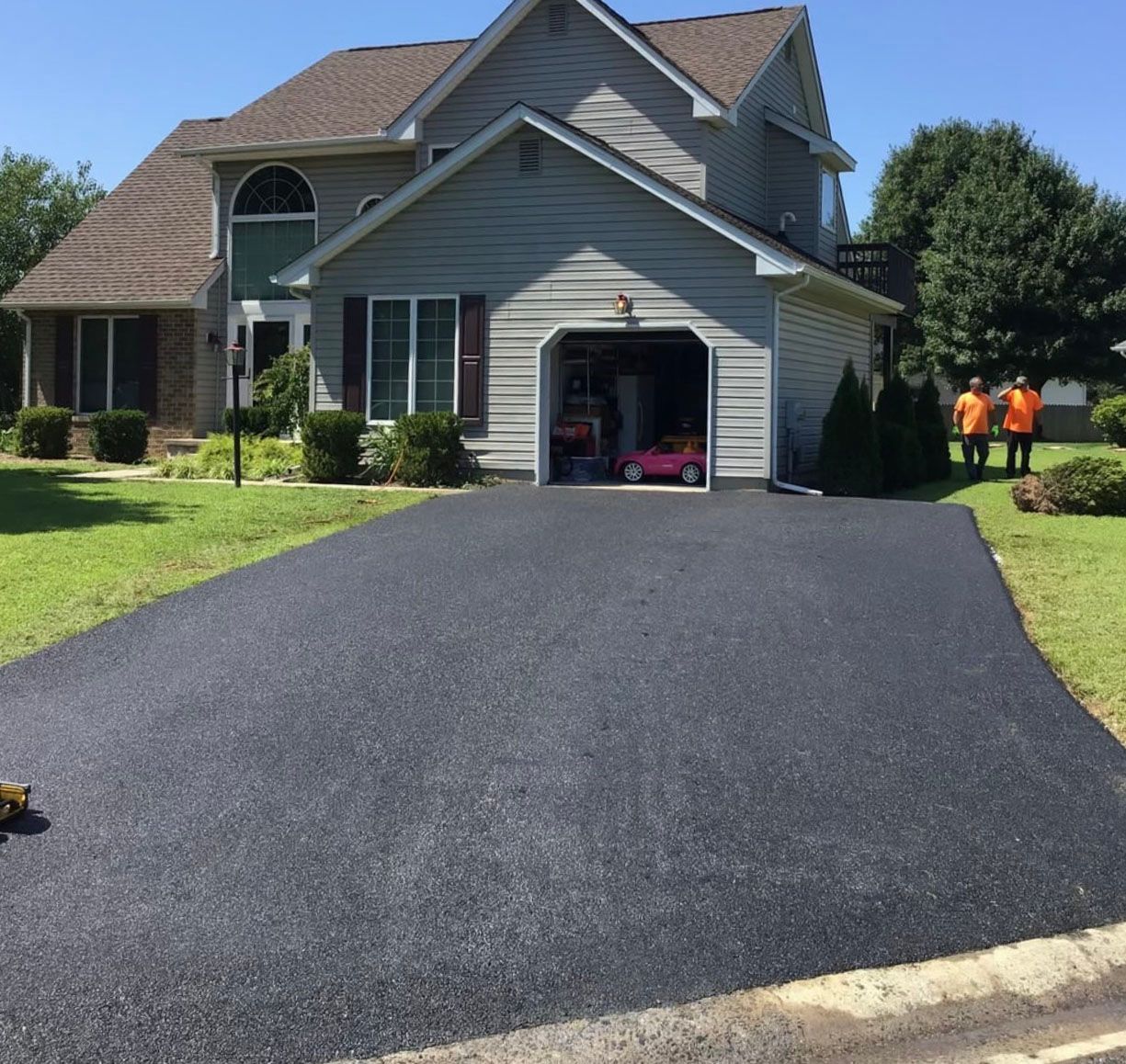 A gray house with a red car in the garage