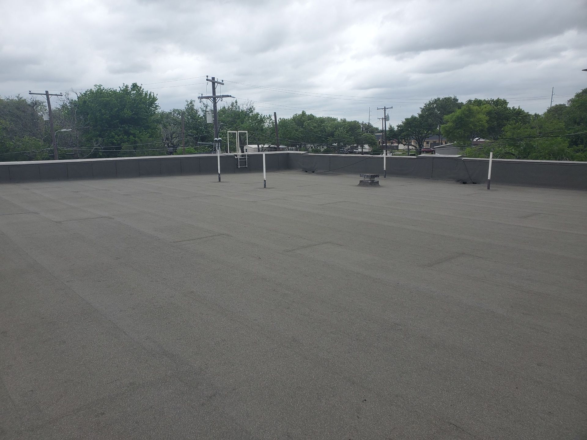 A rooftop with a gray roof and trees in the background - after