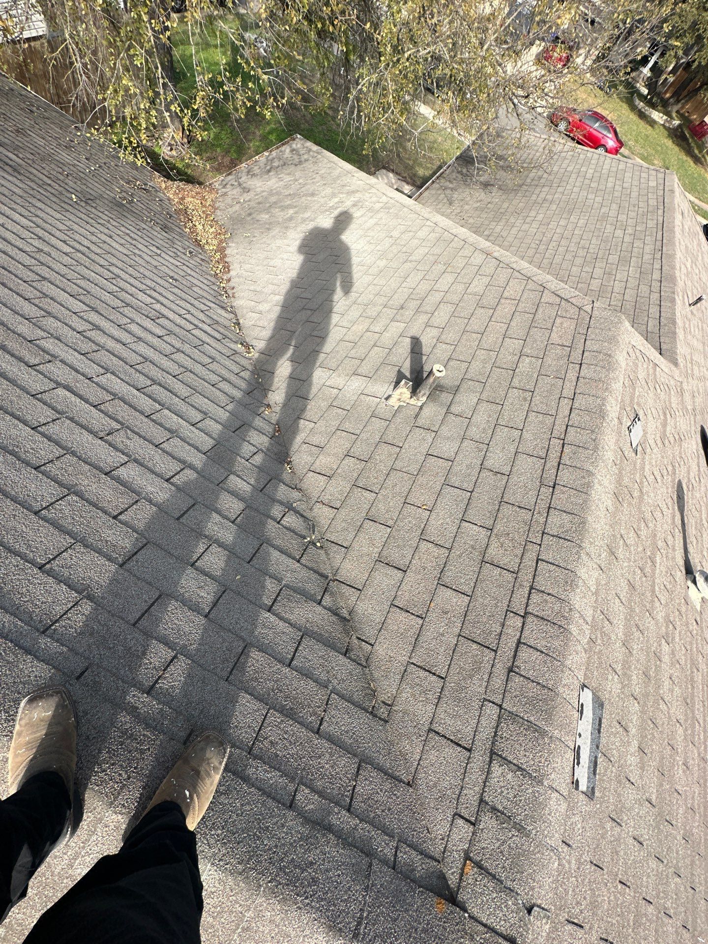 A person is standing on top of a roof with their shadow on it - before