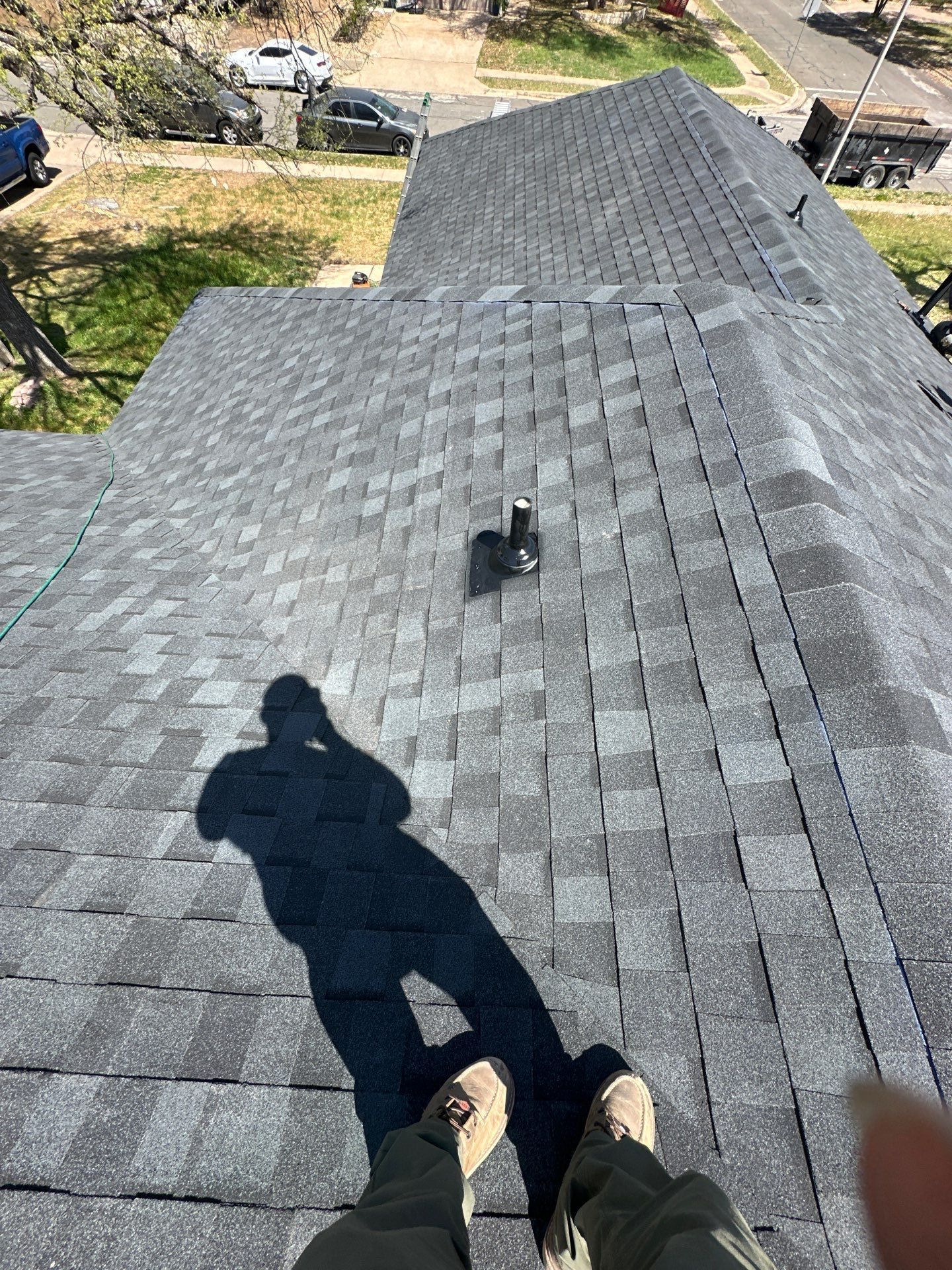 A person is standing on top of a roof with their shadow on it - before