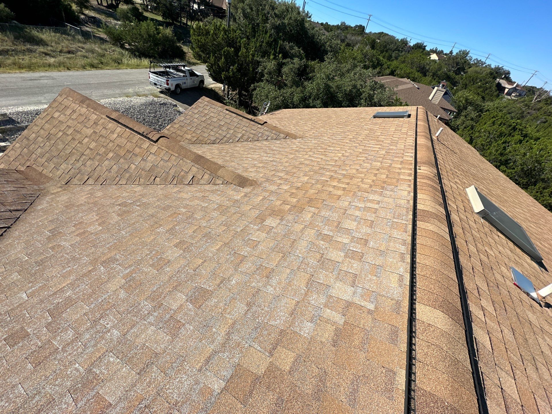A roof with a lot of shingles on it and a truck parked on the side of the road - before