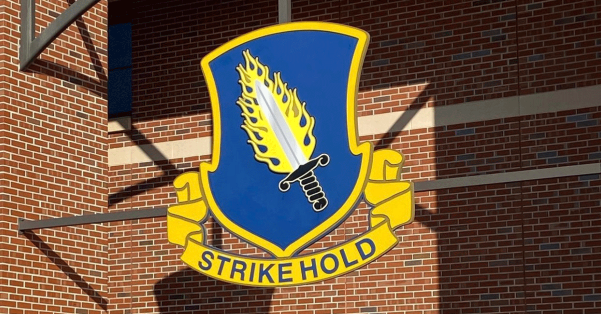 A blue and yellow emblem on a brick wall that says strike hold