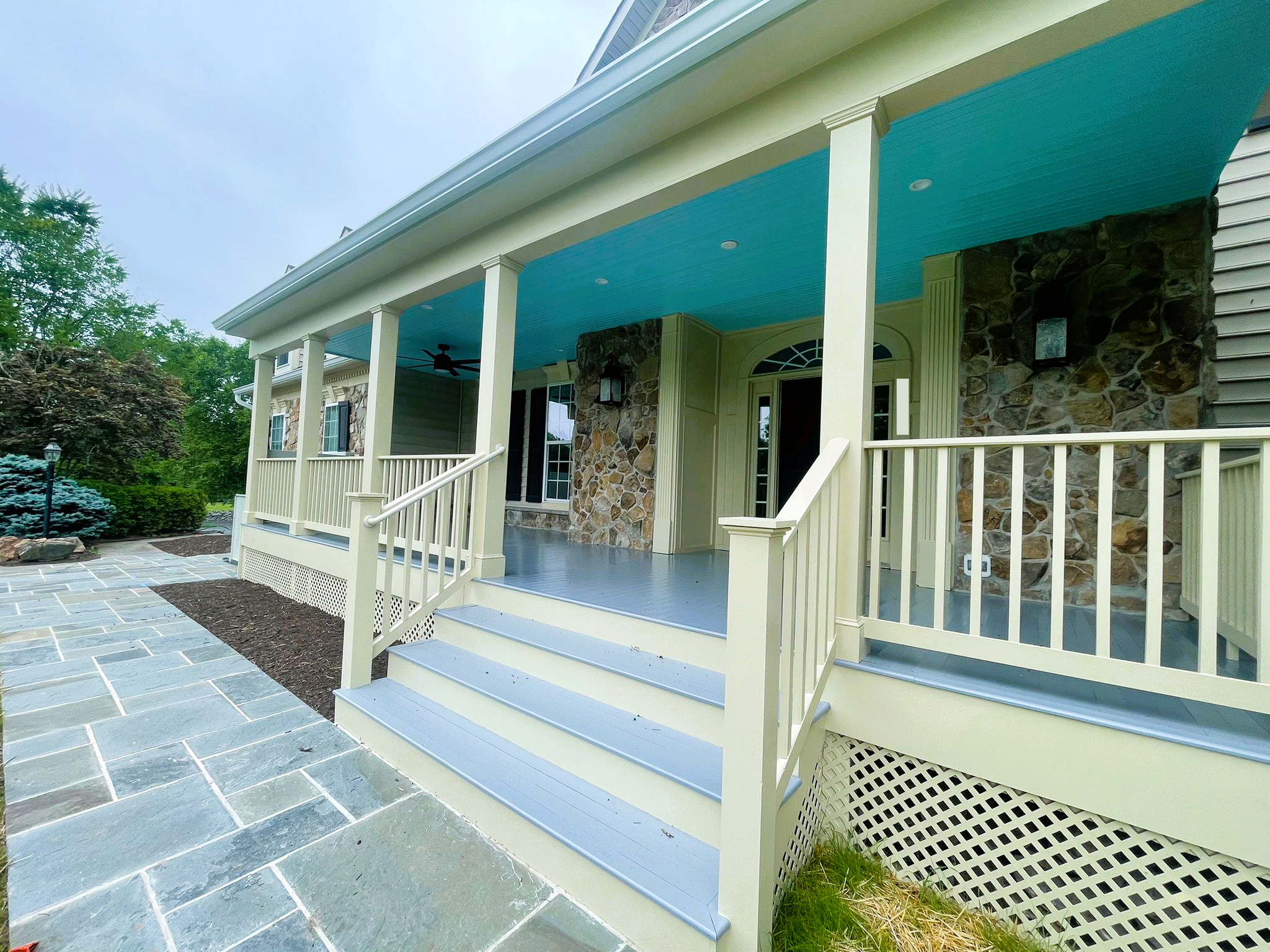 A large porch with stairs and a blue ceiling