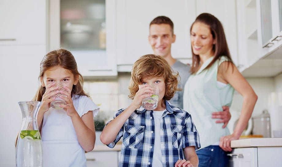 A family is drinking water in the kitchen.