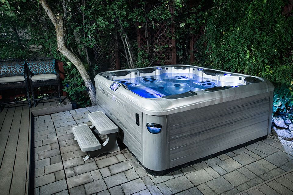 A hot tub is sitting on a patio next to a bench.