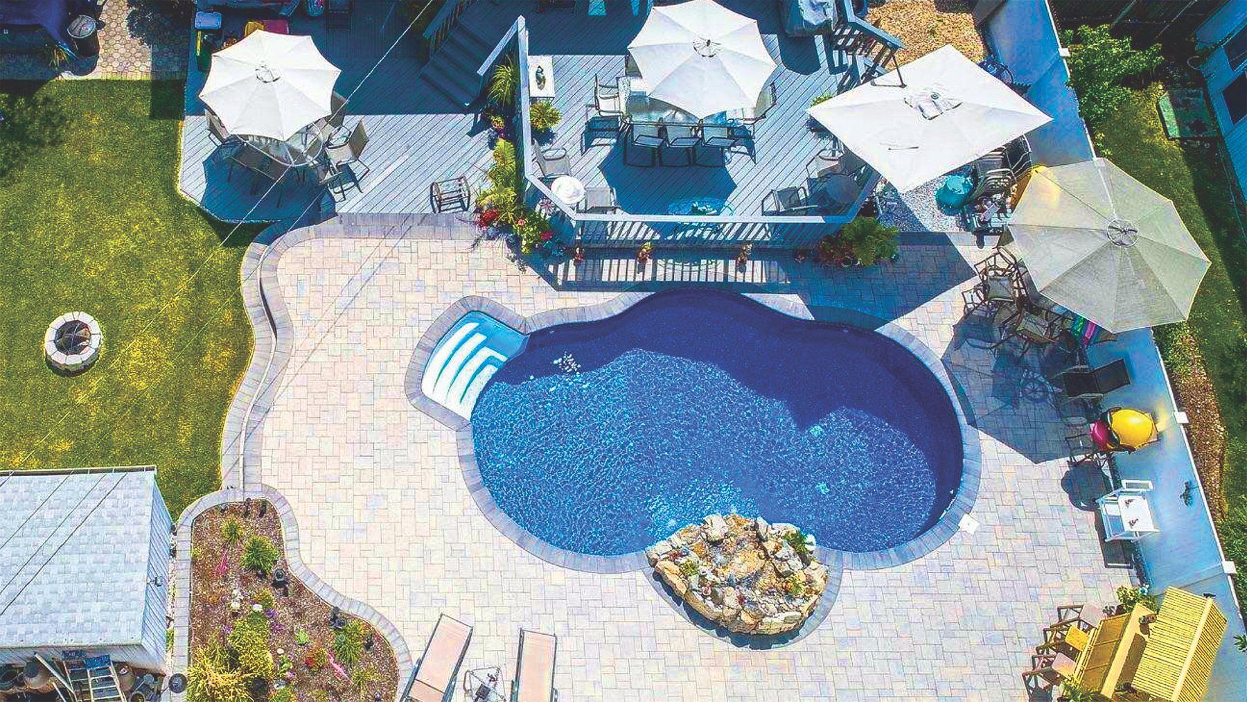 An aerial view of a swimming pool surrounded by umbrellas and chairs.
