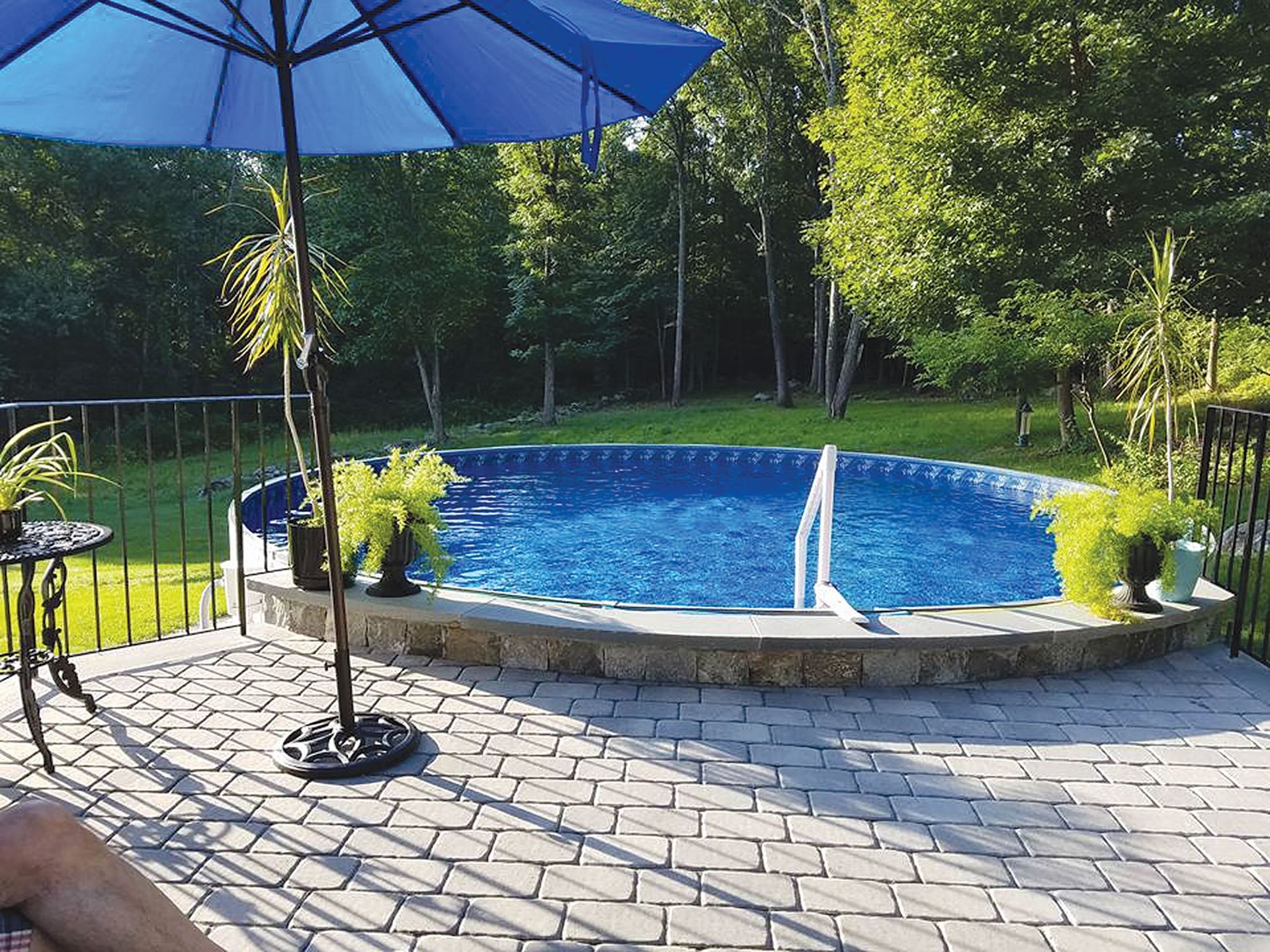 A patio with a swimming pool and a blue umbrella