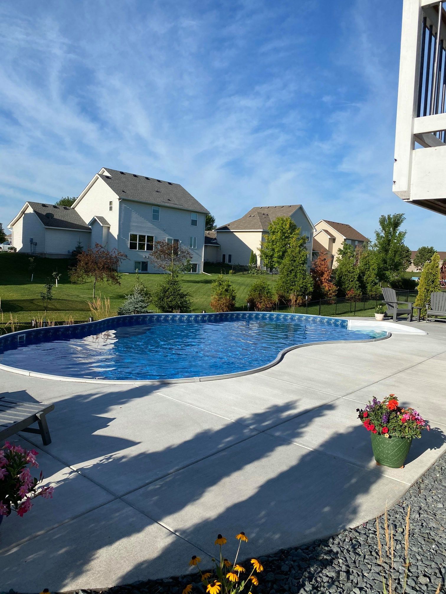 A large swimming pool is in the backyard of a house