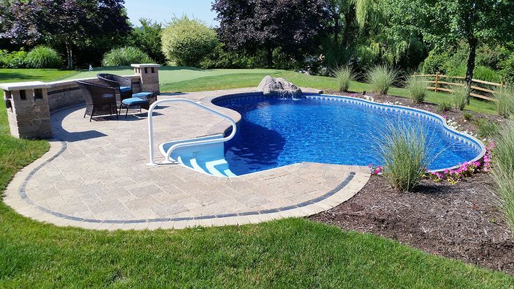 A large blue swimming pool is in the middle of a lush green yard.