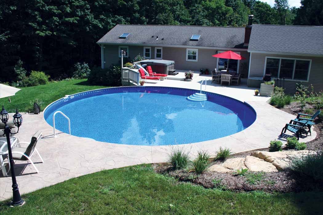 A large round swimming pool is in the backyard of a house.