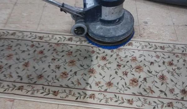 Floor buffer cleaning a patterned tile floor indoors