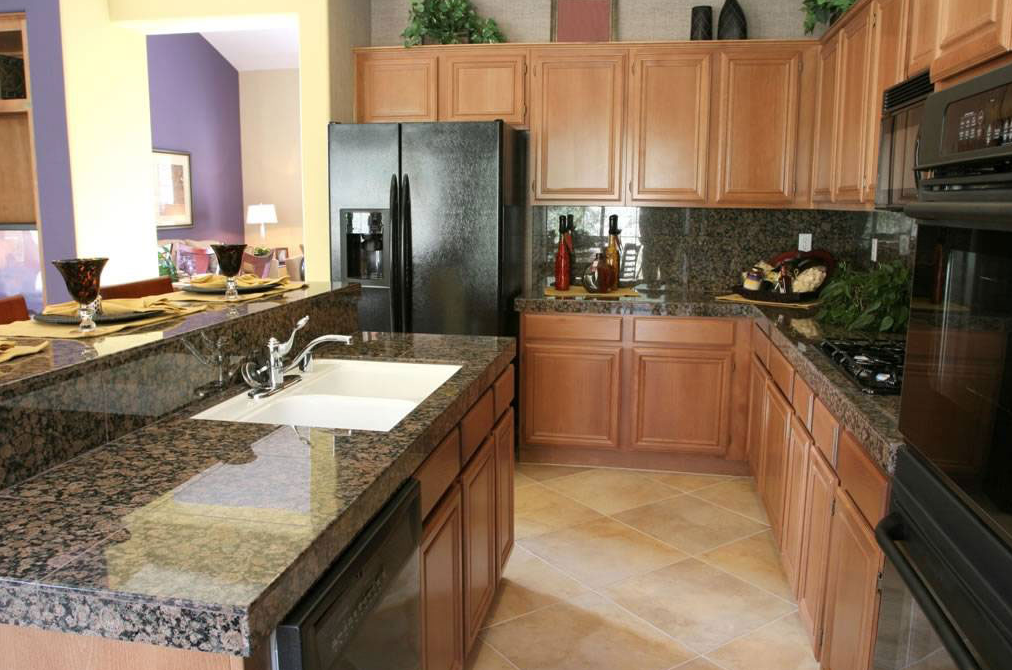 A kitchen with granite counter tops and a black refrigerator