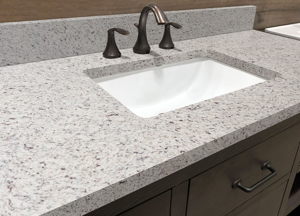A bathroom sink with a granite counter top and a faucet