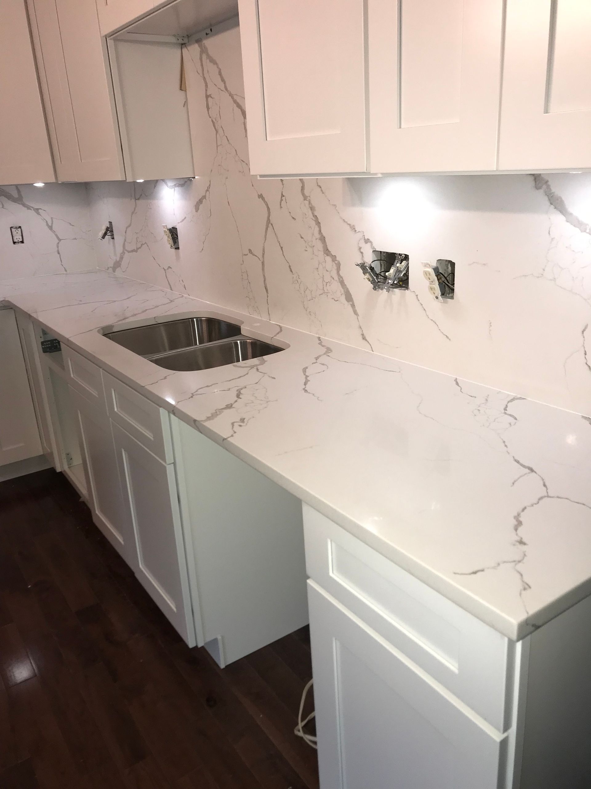 A kitchen with white cabinets and marble counter tops