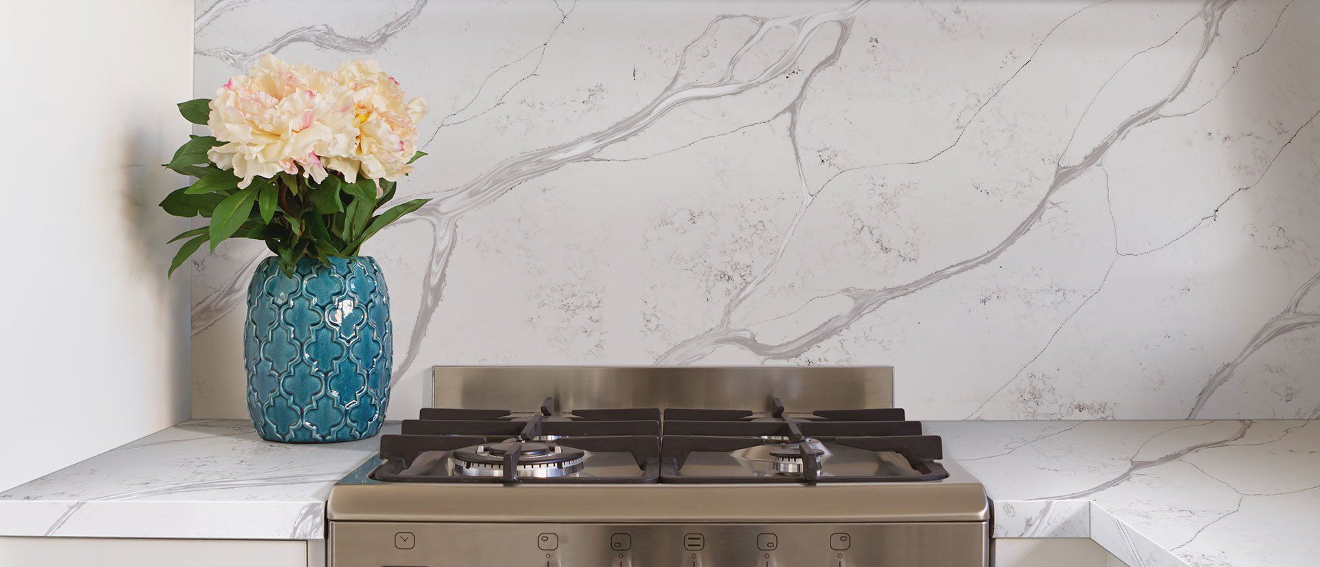 A stove top oven is sitting on a counter next to a vase of flowers.