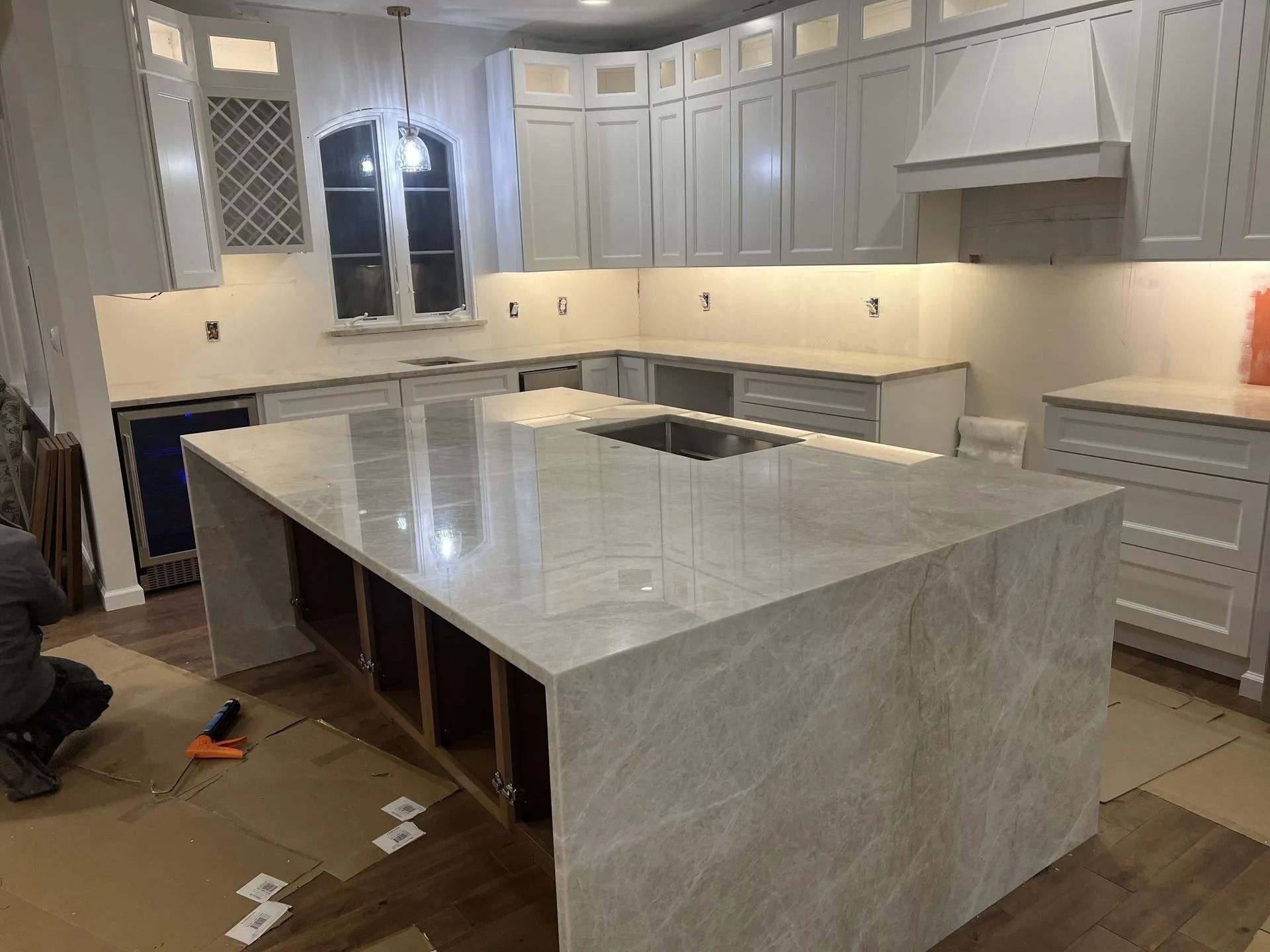 Modern kitchen with gray cabinets and a large marble island under renovation