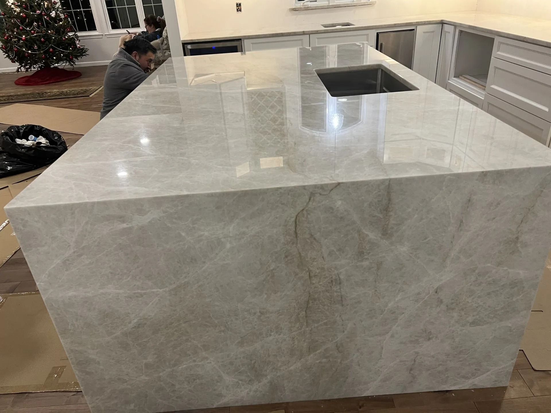 Large white stone kitchen island with sink and cabinets in a modern kitchen.