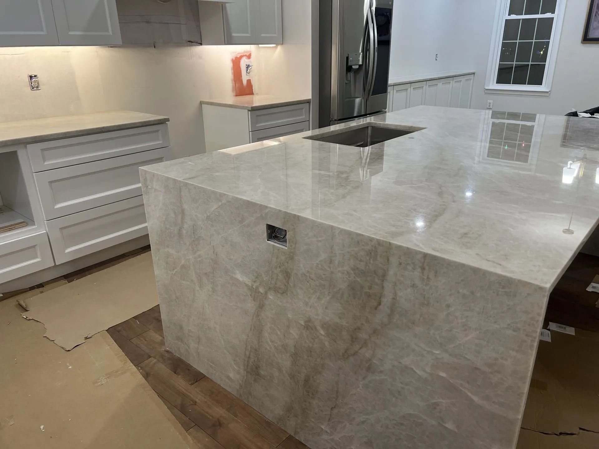 Modern kitchen with marble island and white cabinets, showing a bright open layout.