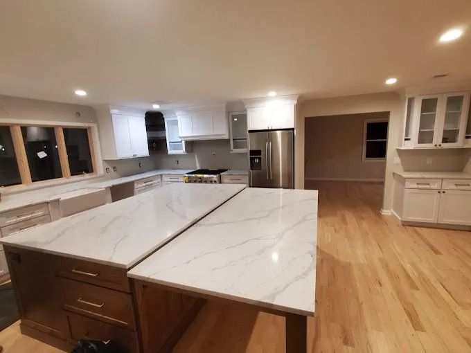 Bright modern kitchen with white marble island, wood floors, and stainless steel appliances