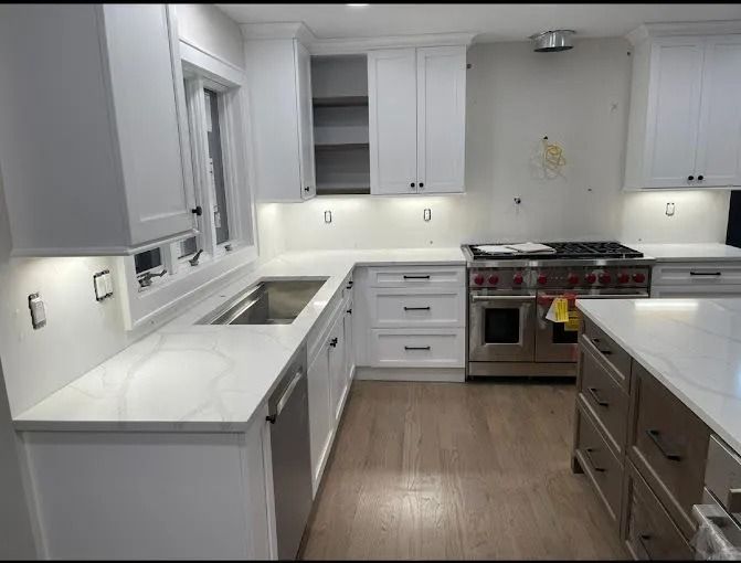 Bright modern white kitchen with stainless steel appliances and wood floor