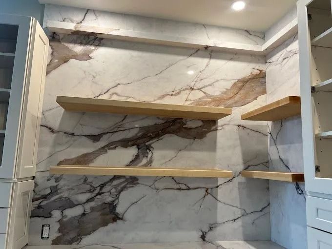 Built-in wall shelving with marble-look backdrop and white cabinets in a modern room