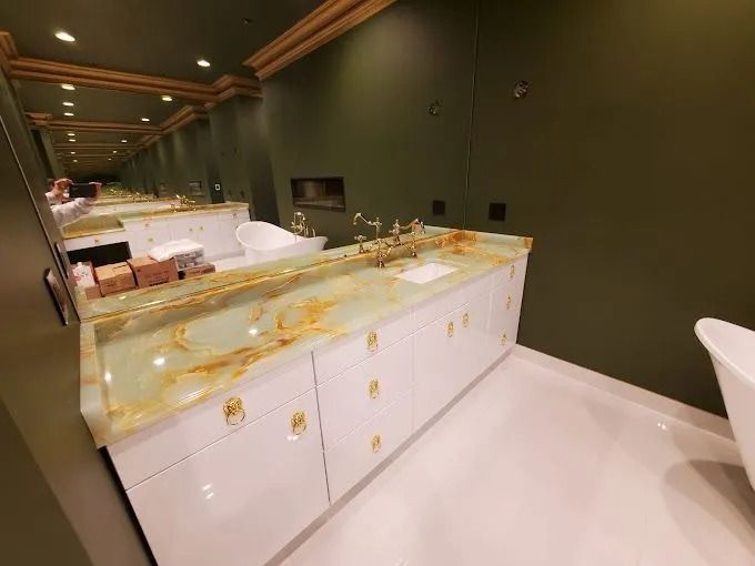 Modern bathroom with white vanity and gold marble countertop against dark green walls