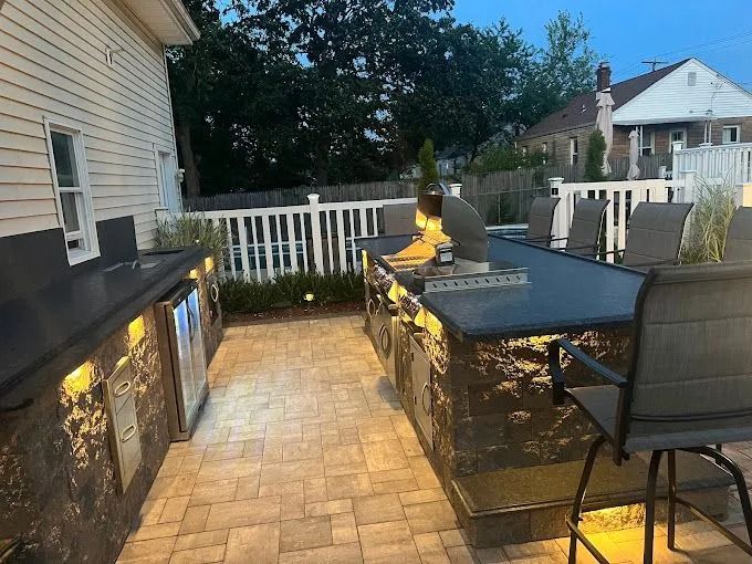 Backyard patio with outdoor kitchen, bar seating, and a fenced deck in sunlight