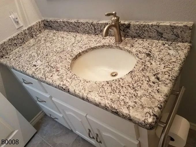 Granite bathroom vanity with white sink, brushed-nickel faucet, and white cabinet doors