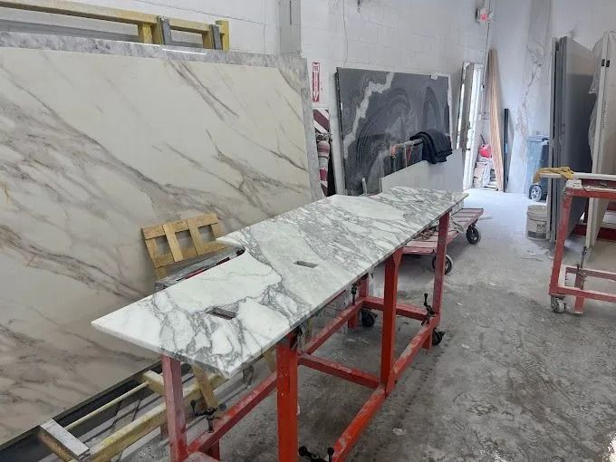 Marble slabs on metal supports in a stone workshop, with tiles and tools in the background.
