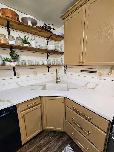 Small kitchen corner with beige cabinets, white countertops, open shelves, and gold faucet.