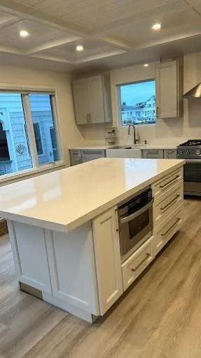 Bright modern kitchen with white island, built-in oven, and windows overlooking a neighborhood view