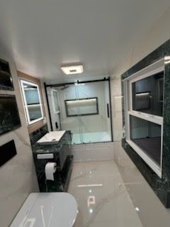 Modern bathroom with black-and-white tile, vanity, toilet, and glass shower enclosure