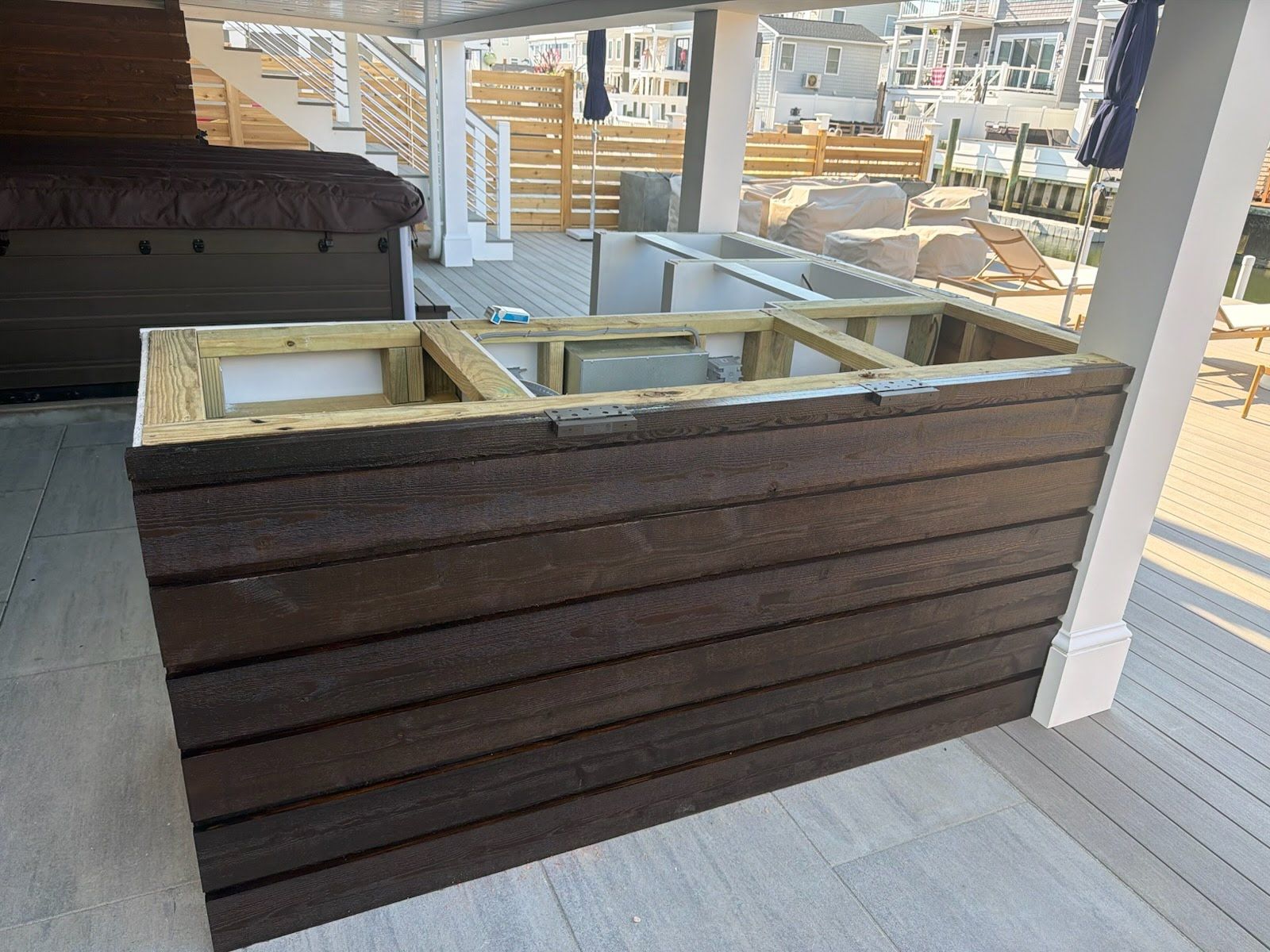 Outdoor wooden bar counter with white sinks and a porch railing in the background