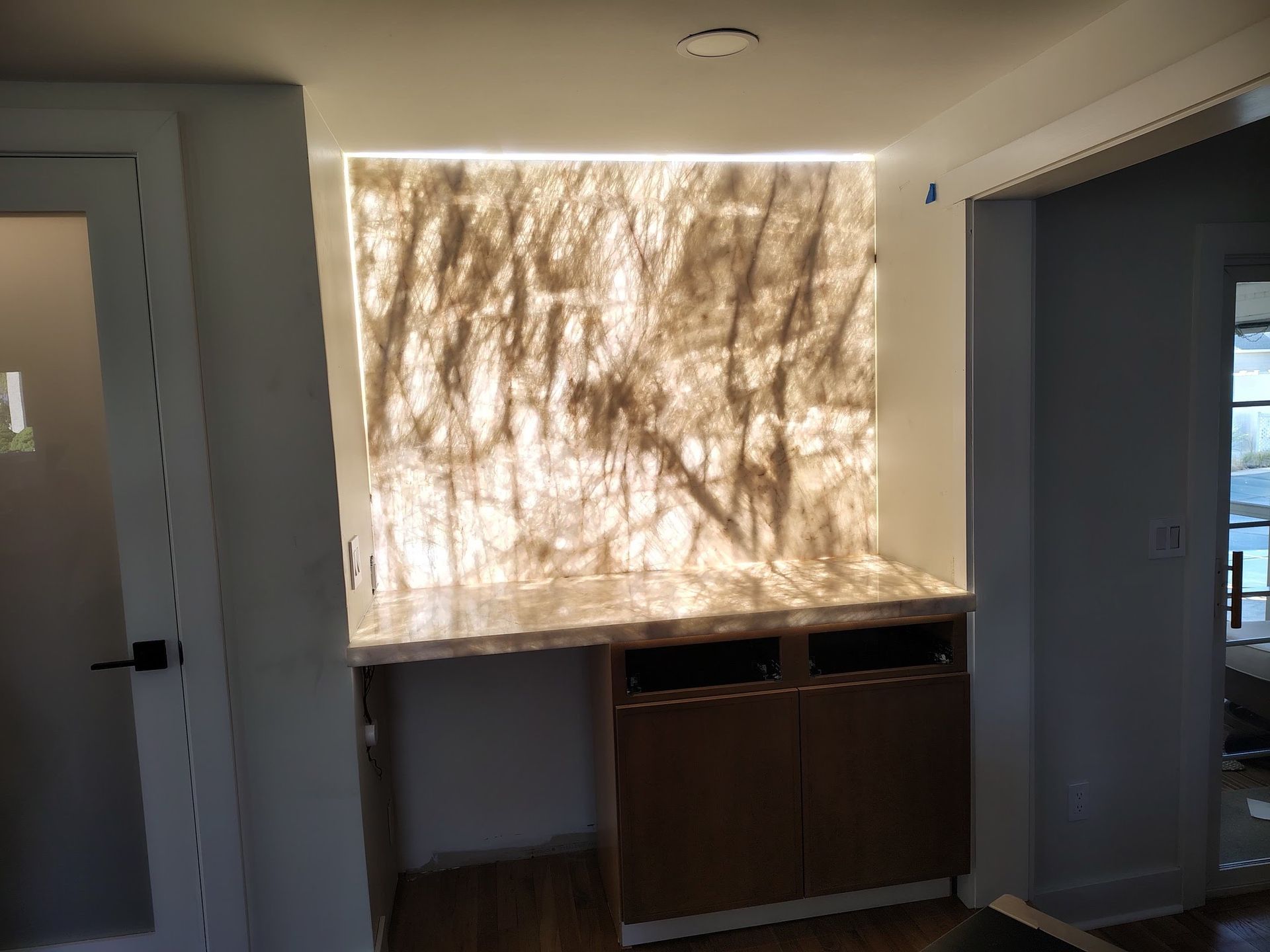 Empty room with a bright window shadow pattern over a countertop and cabinets