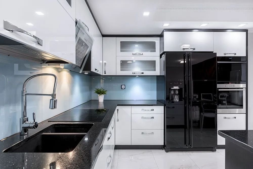 Modern black-and-white kitchen with glossy cabinets, black refrigerator, and double sink under bright lighting